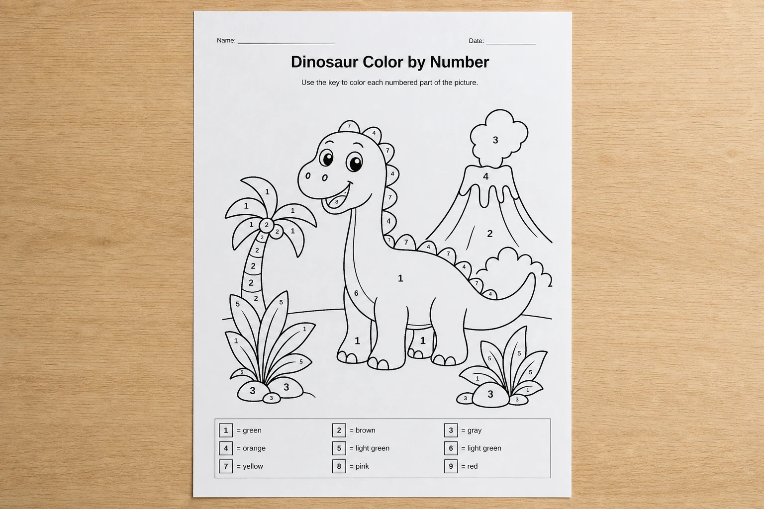 Printed dinosaur color-by-number worksheet on a desk
